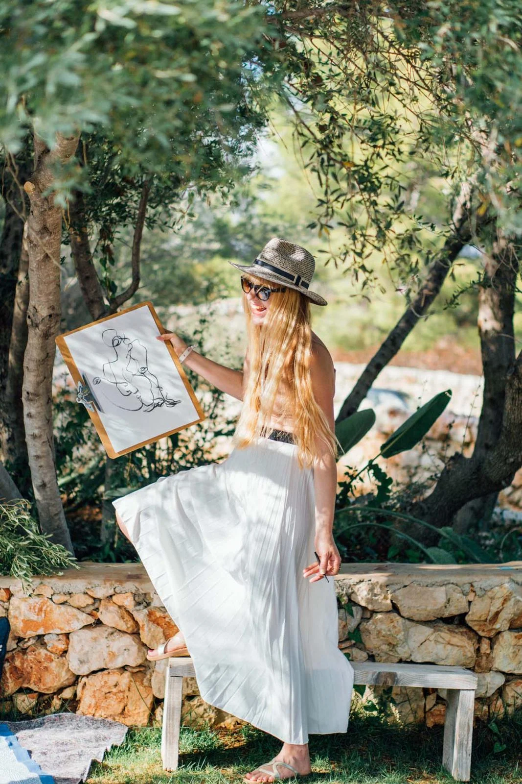Bella holding a drawing in a sunlit olive grove