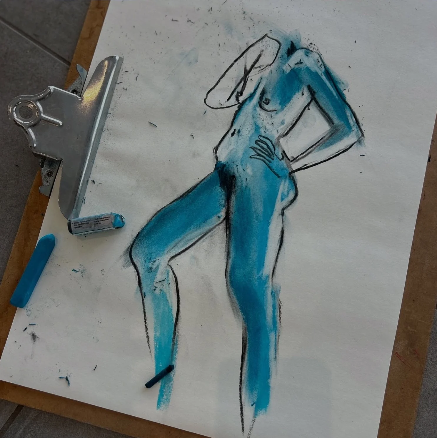 Standing figure drawn in blue pastel on a clipboard