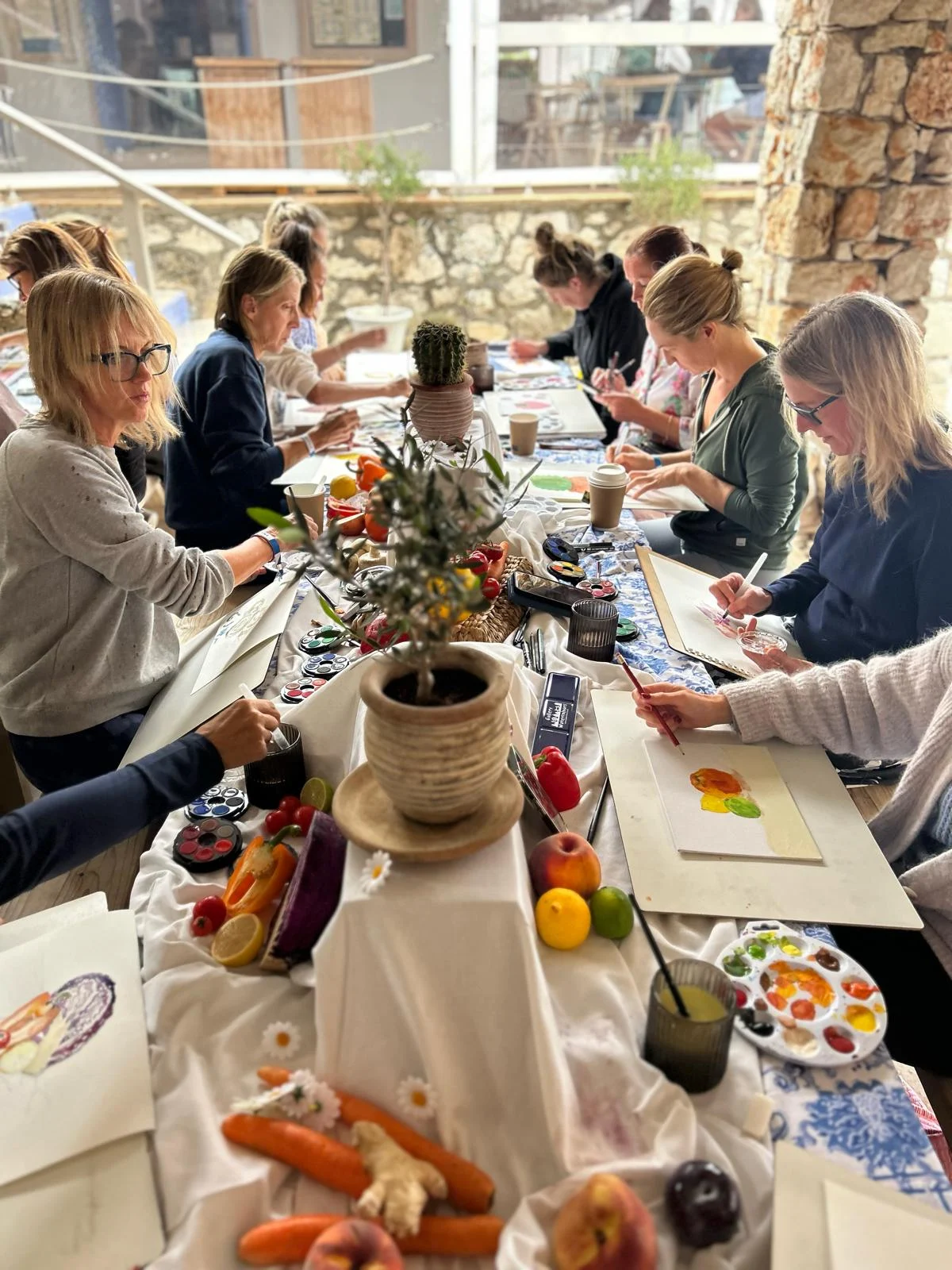 Participants painting a vegetable still life around a shared table
