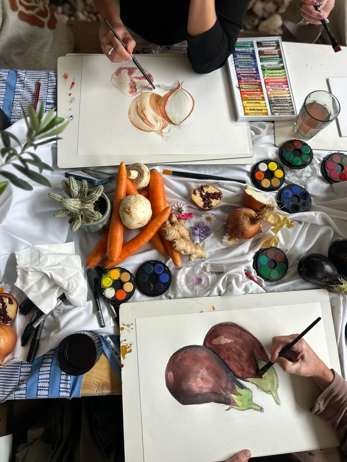 Watercolour study of aubergines and an onion at a painting table